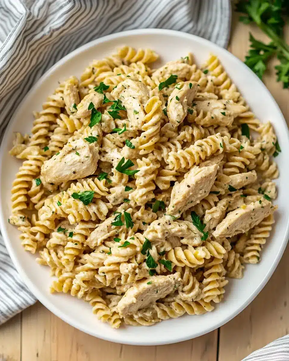 Crockpot Garlic Parmesan Chicken Pasta served with garnishes.