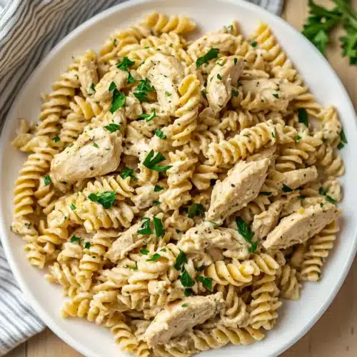 Crockpot Garlic Parmesan Chicken Pasta served with garnishes.
