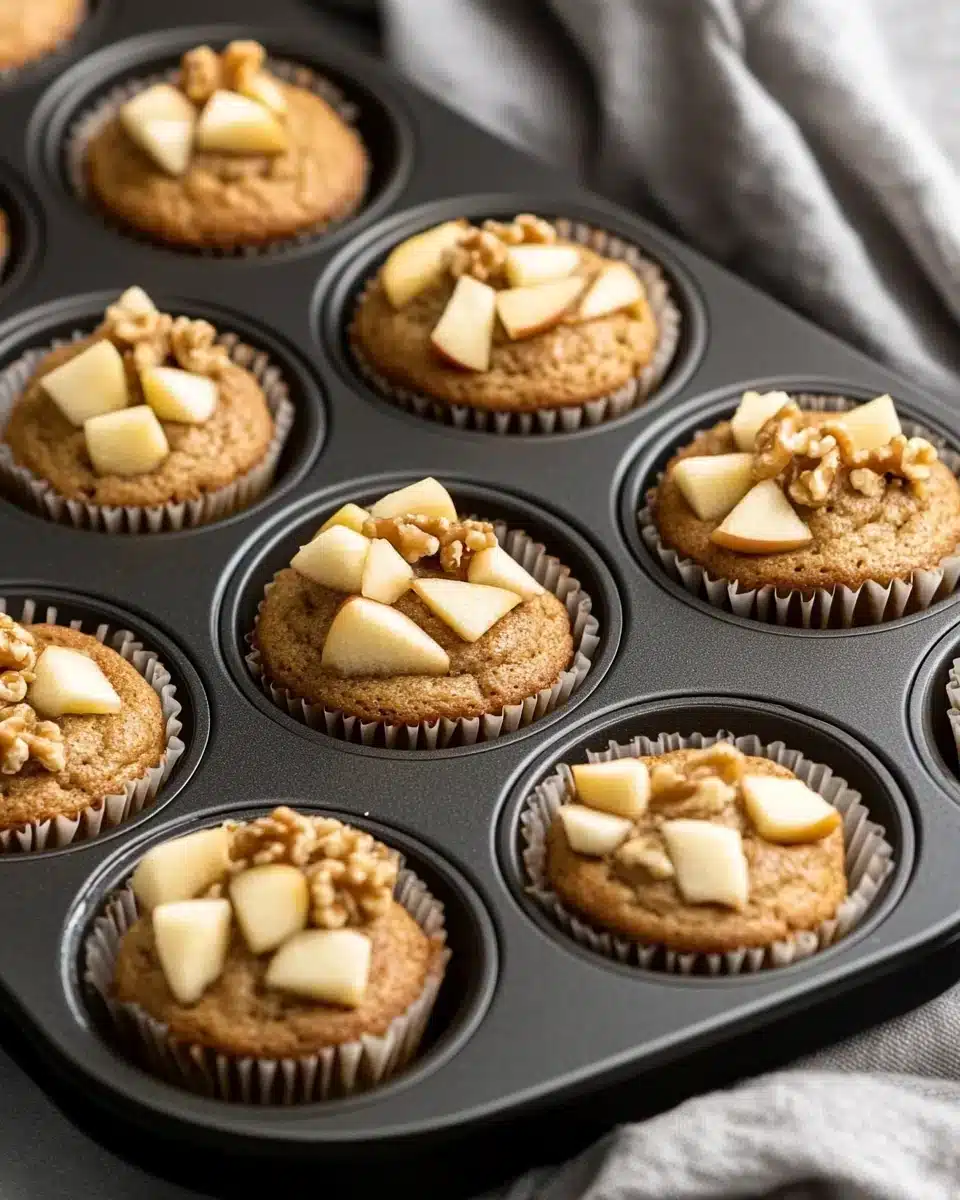 Delicious Caramel Apple Cupcakes in a muffin tin with apple pieces.