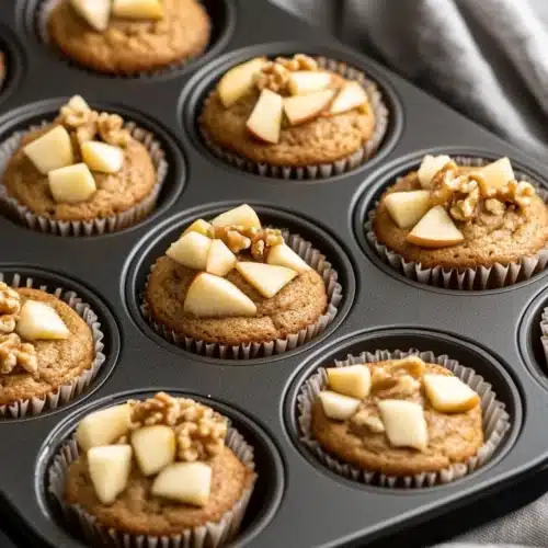 Delicious Caramel Apple Cupcakes in a muffin tin with apple pieces.