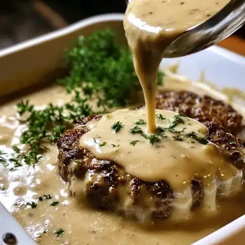 Amish Hamburger Steak Bake with creamy gravy and fresh herbs.