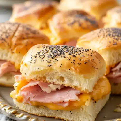 Delicious Baked Ham and Cheese Sliders on a decorative plate.
