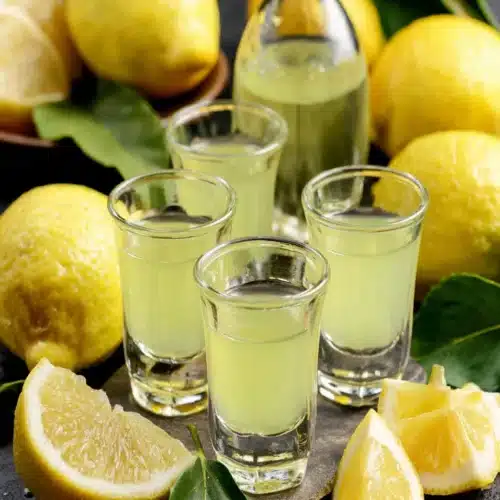 Delicious homemade limoncello served with fresh lemons.