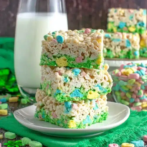 Colorful Lucky Charms Rice Krispie Treats stacked on a plate.