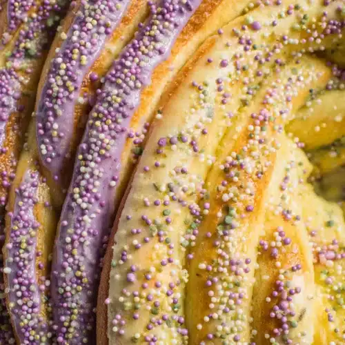 Delicious sourdough king cake topped with icing and colorful sprinkles.