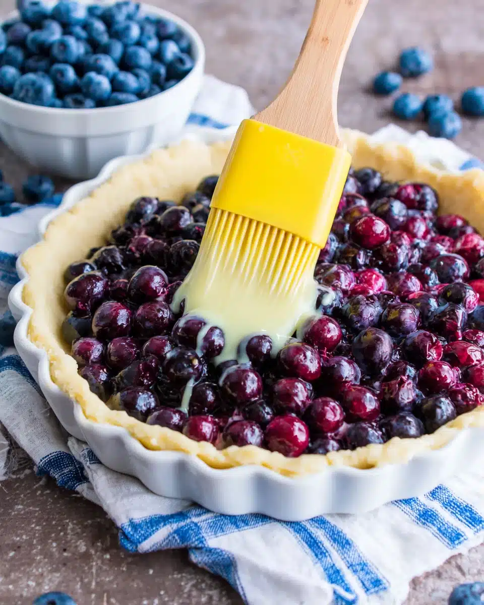 Delicious Blueberry Tart Preparation Brushing a blueberry tart with egg wash for a golden crust.