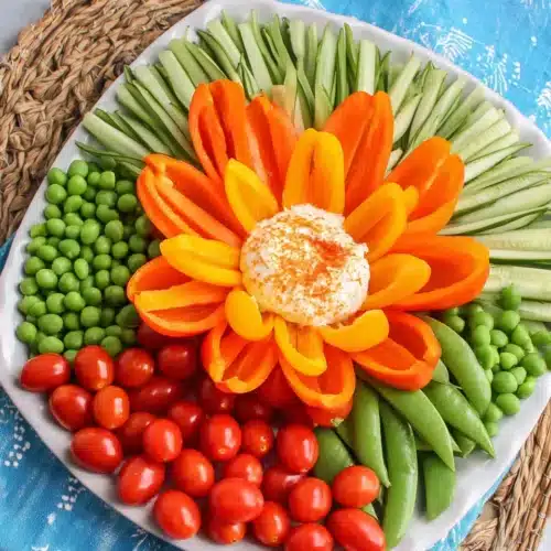 Vibrant flower veggie tray with bell peppers and ranch dip.
