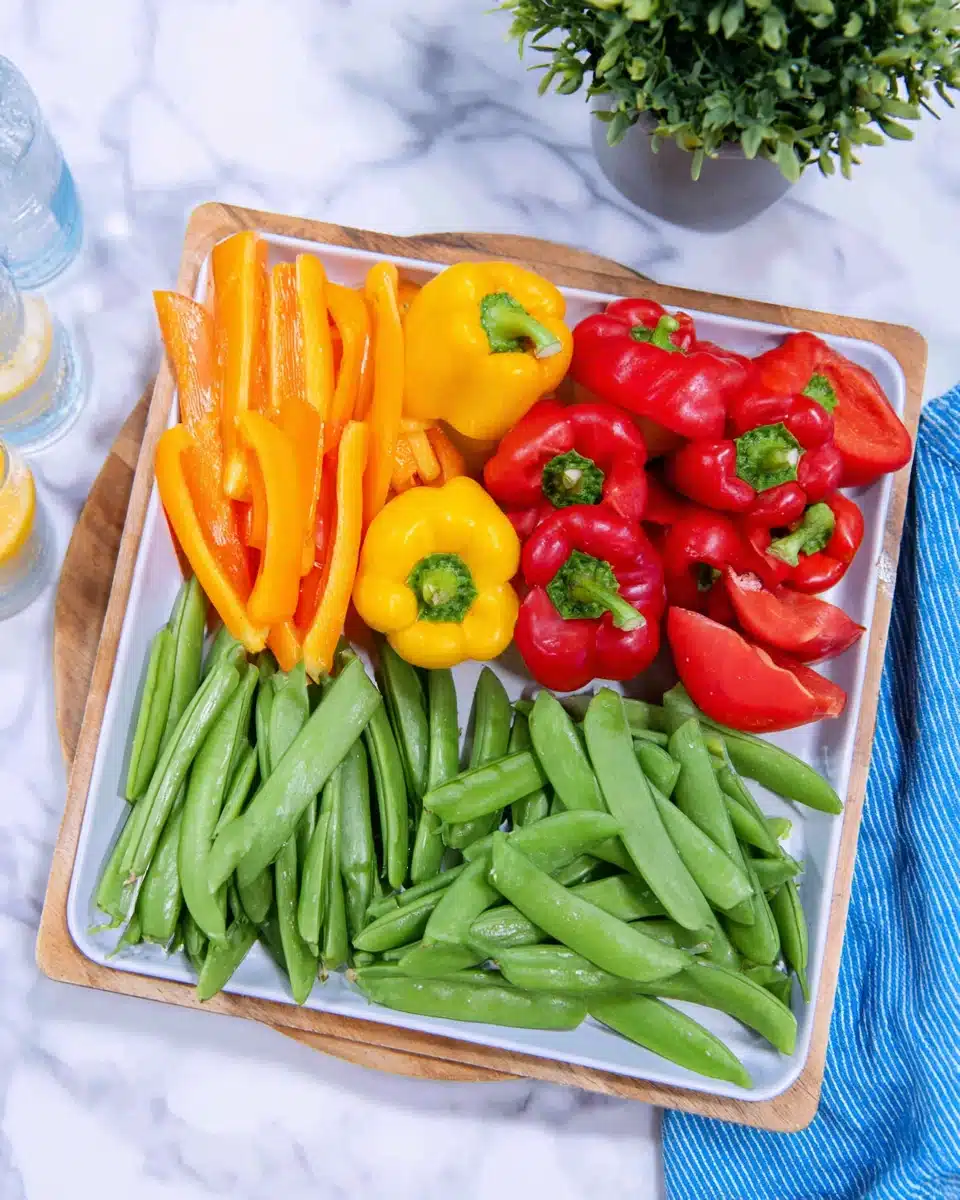 Colorful flower veggie tray with bell peppers and snap peas.