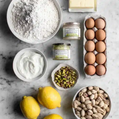 Lemon pistachio cake ingredients on a marble counter.