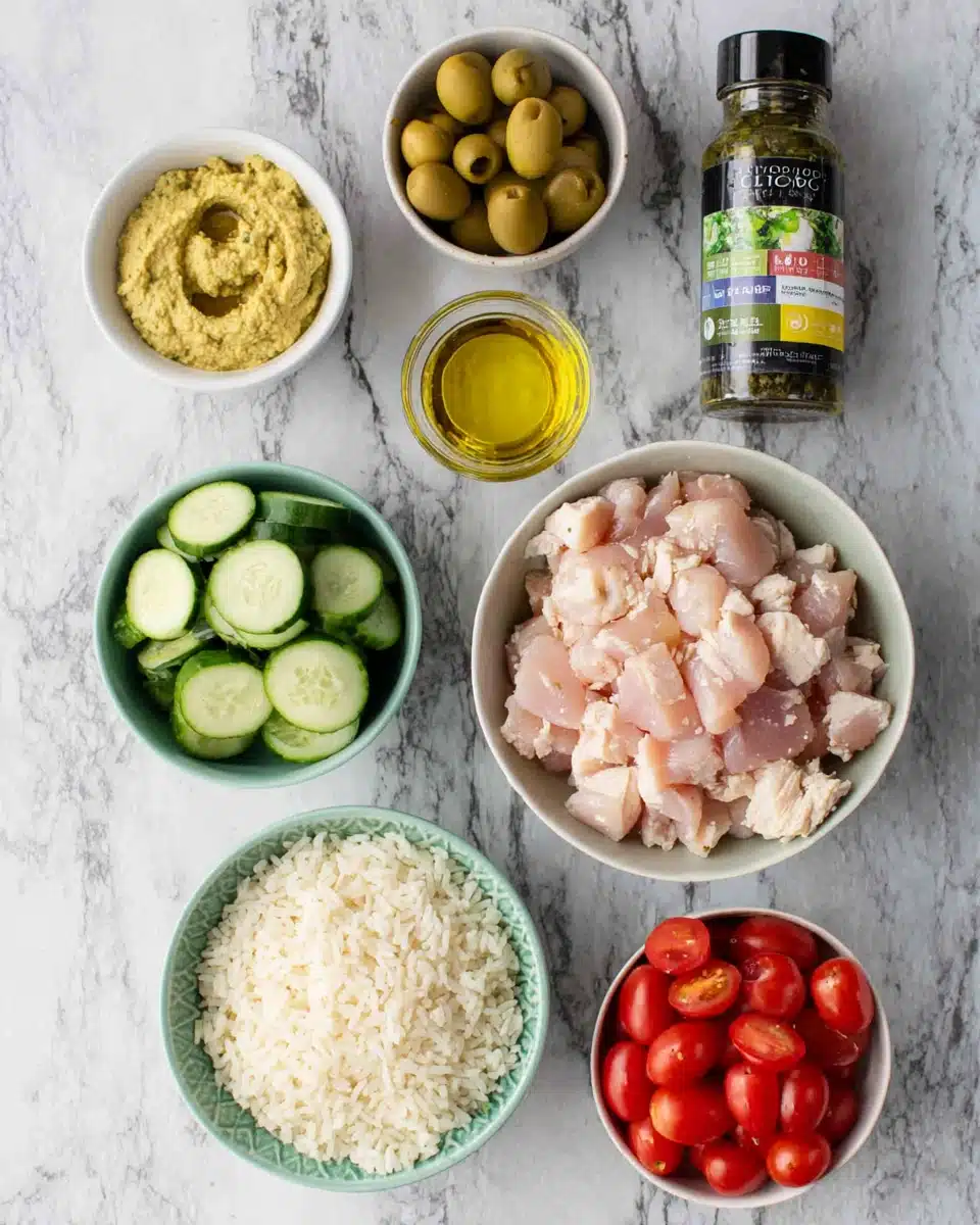 Mediterranean chicken bowls ingredients: chicken, rice, veggies, and hummus.