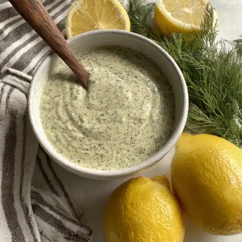 Creamy lemon dill dressing in a bowl with fresh ingredients.