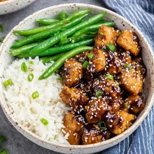 Delicious sesame chicken served with rice and green beans.