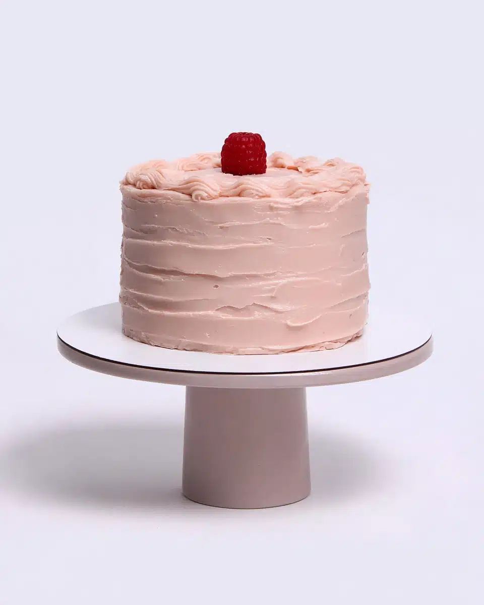 Thiebaud Pink Cake with buttercream frosting and raspberry on top.
