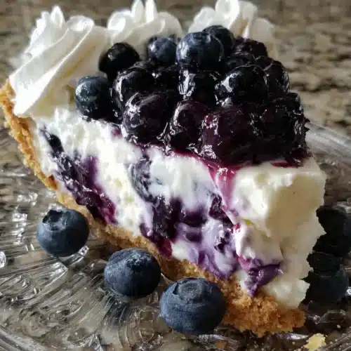 Slice of blueberry cream cheese pie with fresh berries and whipped cream