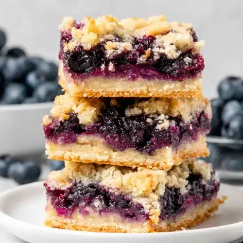 Stack of three blueberry crumble bars with golden topping and juicy filling