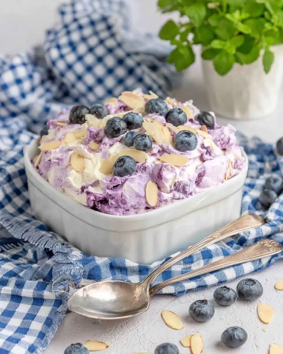 Creamy blueberry fluff salad topped with fresh blueberries and almonds in a white bowl