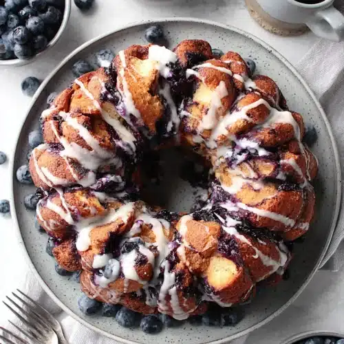 Blueberry monkey bread with white glaze and fresh blueberries on a plate