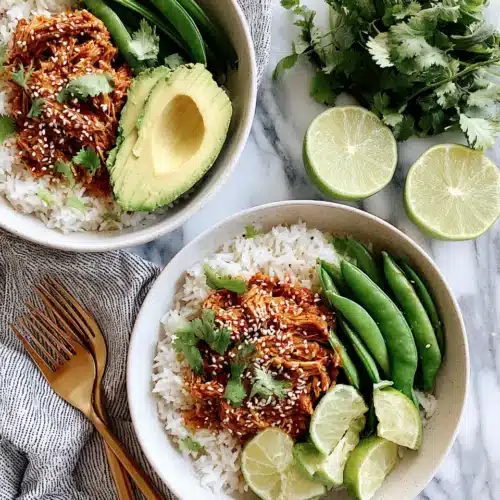 Delicious Chicken Recipe with Coconut Rice 1 Chicken recipe with coconut rice served with avocado, snap peas, and lime on white plates.