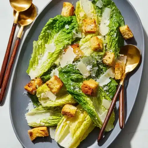 Classic Caesar salad with romaine, croutons, and Parmesan on a gray plate