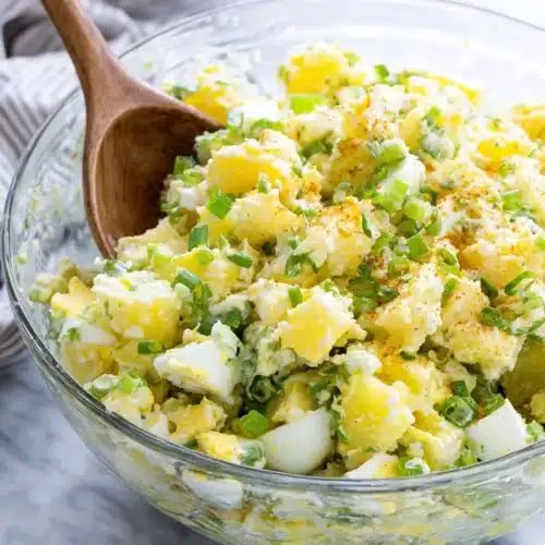 Classic potato salad with eggs and celery in a glass bowl