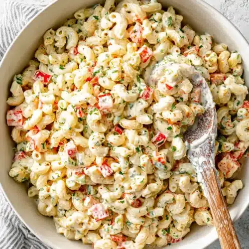 Creamy cold macaroni salad with vegetables and herbs in a white bowl