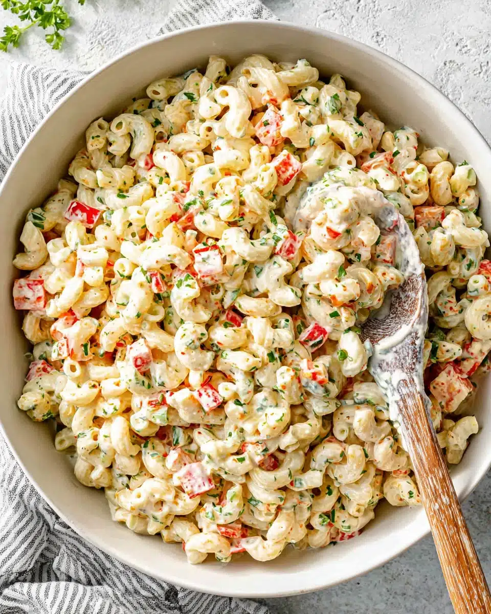 Creamy cold macaroni salad with vegetables and herbs in a white bowl