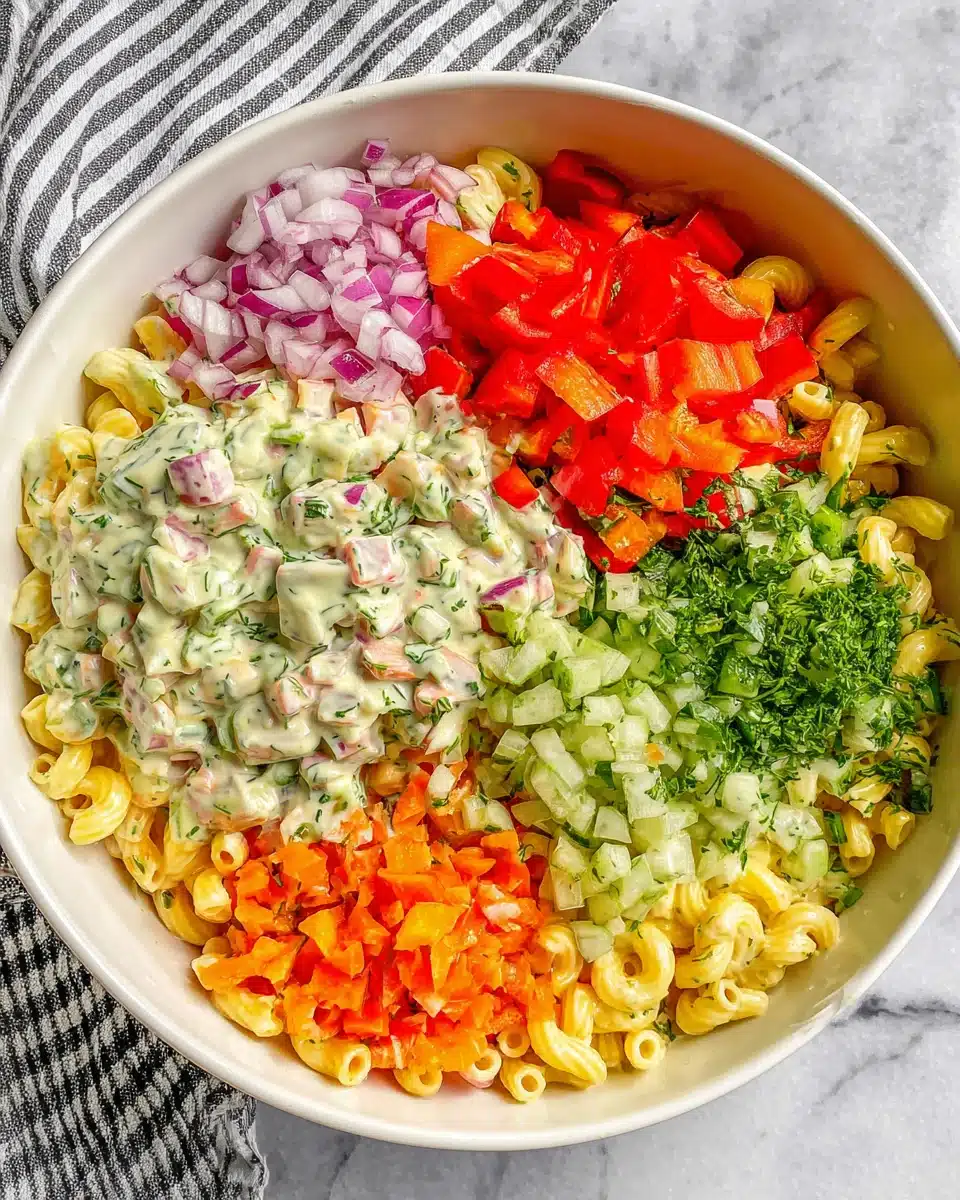 Cold macaroni salad with colorful vegetables and creamy dressing in a white bowl