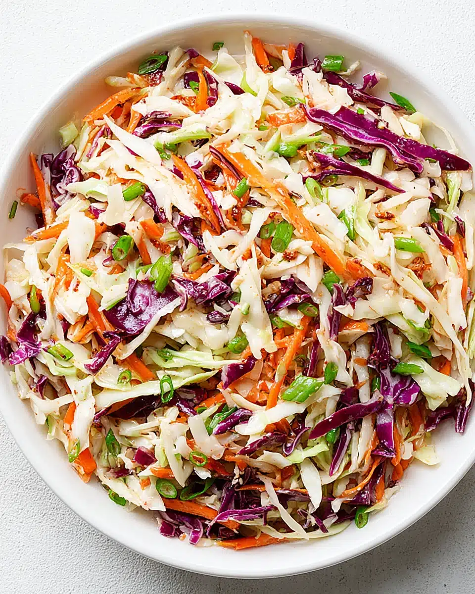 Coleslaw for pulled pork with green and red cabbage, carrots, and green onions in a white bowl