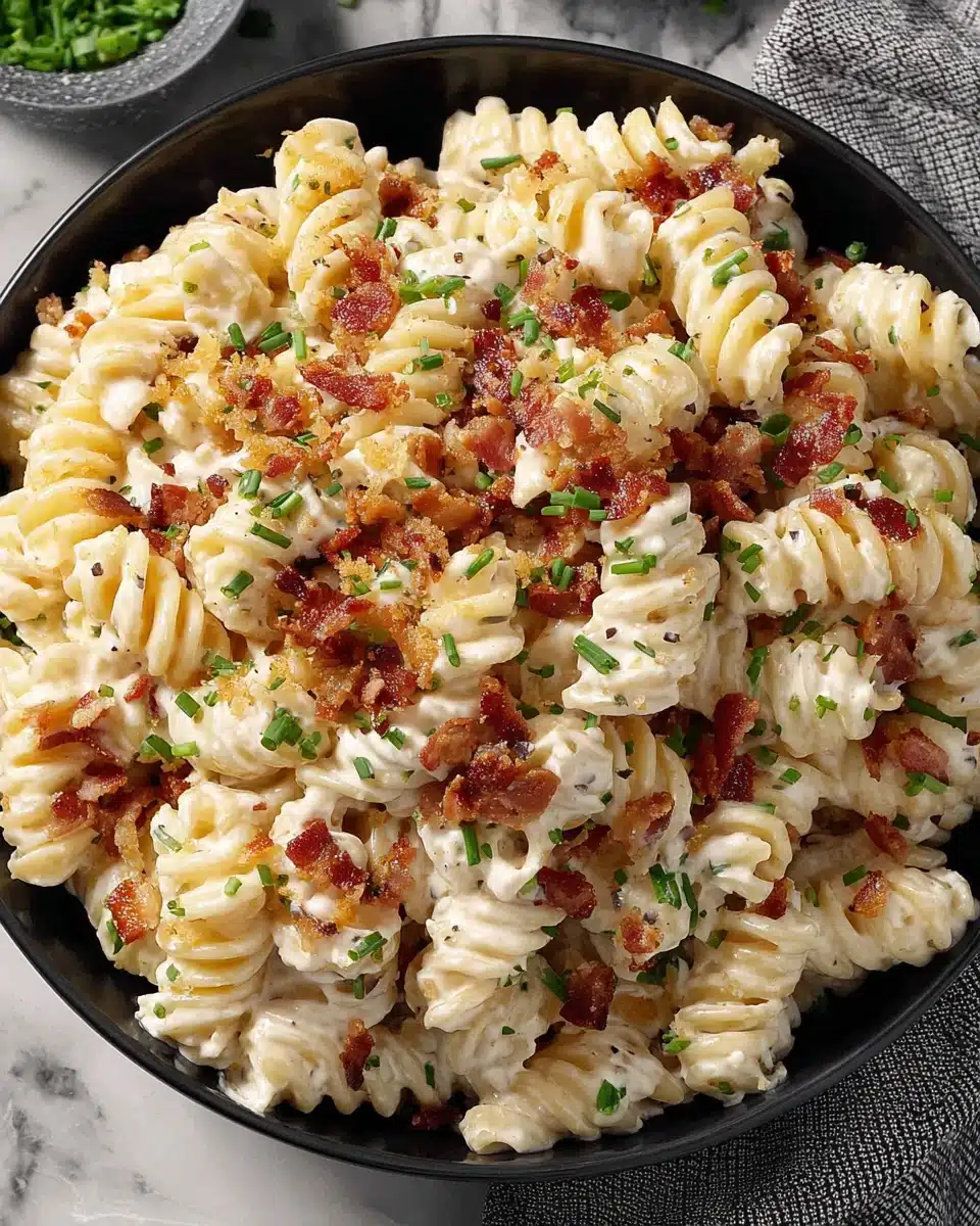 Creamy bacon cheddar ranch pasta salad with crispy bacon and green onions in a black bowl