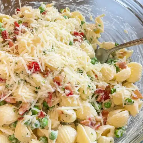 Creamy Pea and Bacon Pasta Salad: A Delicious Delight 1 Creamy pea and bacon pasta salad with shredded Parmesan cheese in a glass bowl