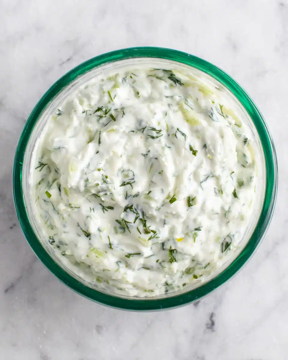 Easy Homemade Tzatziki Sauce Recipe Creamy homemade tzatziki sauce in a glass bowl with herbs and cucumber