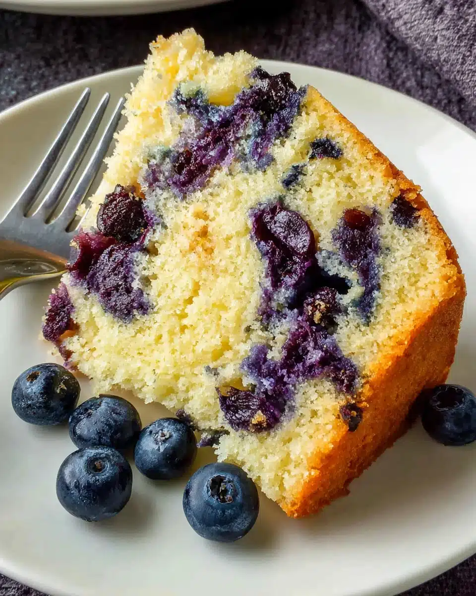 Moist eggless blueberry cake slice with fresh blueberries on a plate