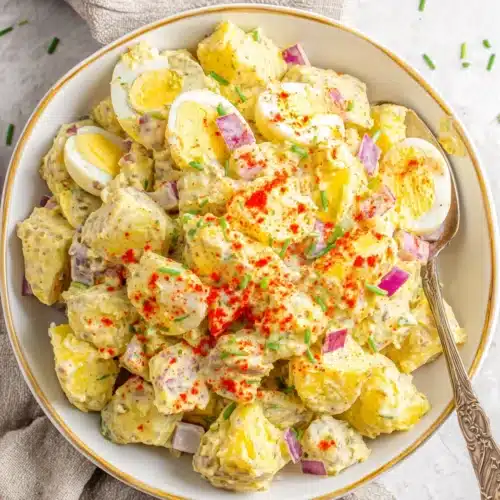 Creamy ever potato salad with paprika and eggs in a white bowl