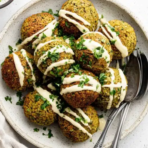 Crispy falafel balls with tahini sauce and fresh herbs on a plate