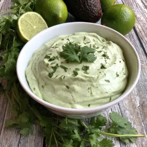 Fresh Avocado Cream Sauce: A Creamy Delight 1 Fresh avocado cream sauce in a white bowl with cilantro, lime, and avocado