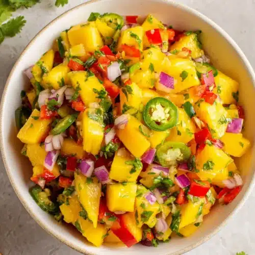 Fresh mango salsa with diced mango, peppers, onions, and cilantro in a bowl