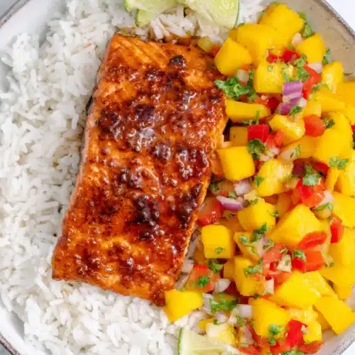 Honey lime salmon with mango salsa on rice, garnished with lime