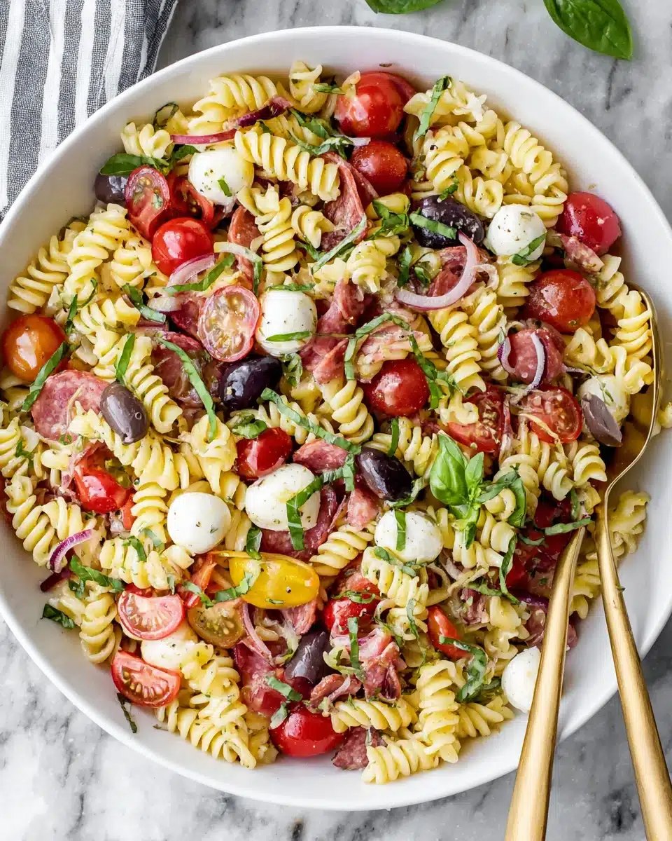 Italian Pasta Salad with Olive and Mango Italian pasta salad with olive and mango in a white bowl, featuring fusilli, tomatoes, olives, and cheese