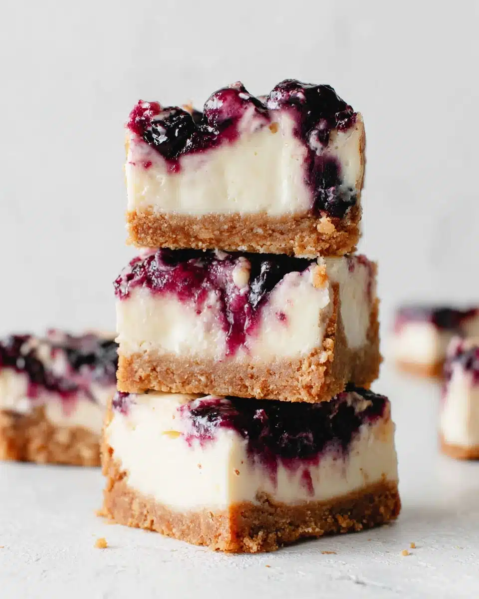 Stacked lemon blueberry cheesecake bars with creamy filling and blueberry swirl