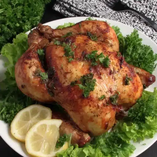 Lemon Butter Roasted Chicken: A Delicious Family Favorite 1 Lemon butter roasted chicken with herbs and lemon slices on a white plate