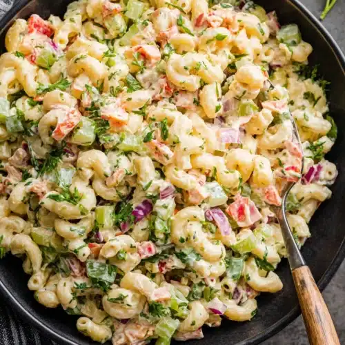 Creamy macaroni salad with colorful veggies in a black bowl