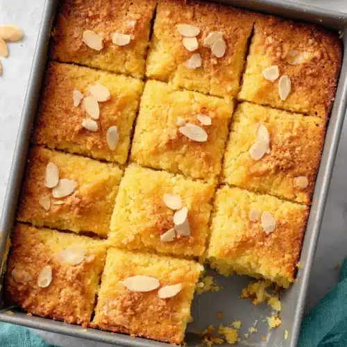 Nutty golden cake with crunchy topping in a baking pan, topped with almonds