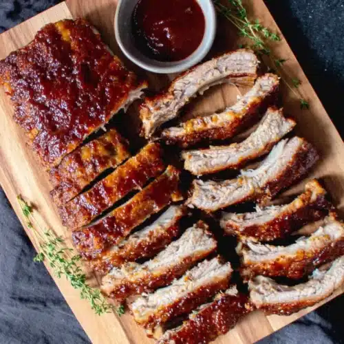Oven baked ribs with homemade sauce, sliced on a wooden board