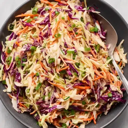 Perfect slaw recipe with colorful cabbage, carrots, and green onions in a bowl