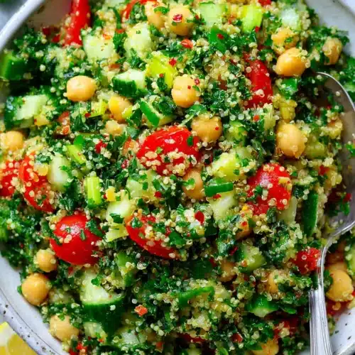 Quinoa chickpea tabbouleh salad with fresh herbs, tomatoes, and cucumbers in a white bowl