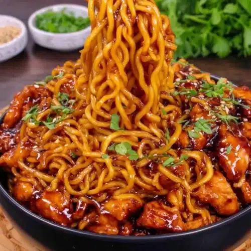 Sticky Garlic Chicken Noodles: A Delightful Family Favorite 1 Sticky garlic chicken noodles with glossy sauce, chicken, and green onions in a black bowl