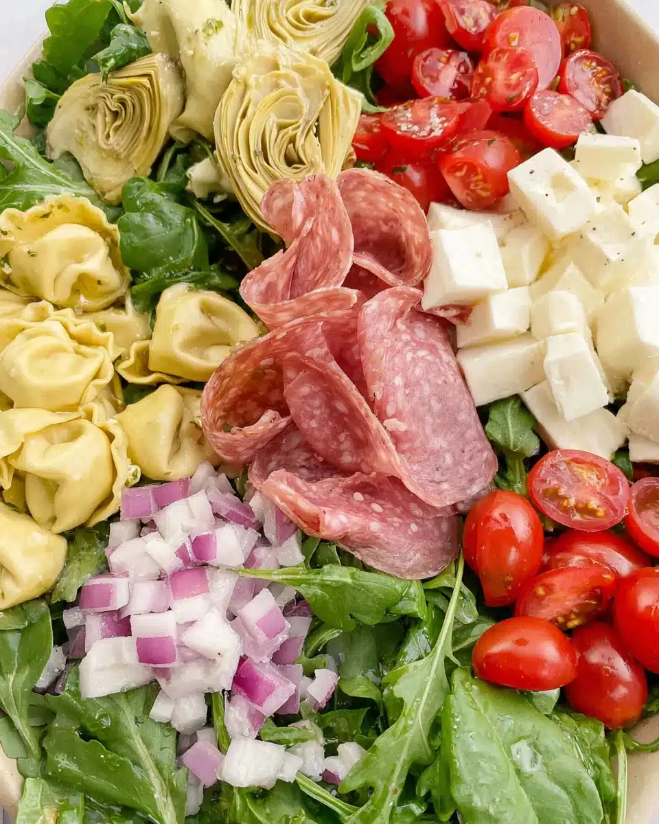 Tortellini Antipasto Salad with Fresh Greens and Meats Tortellini and antipasto salad with fresh greens, salami, tomatoes, and mozzarella