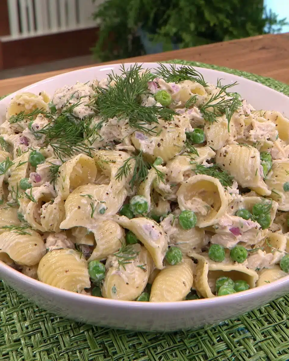 Creamy tuna noodle pasta salad with shell pasta, peas, and dill in a white bowl