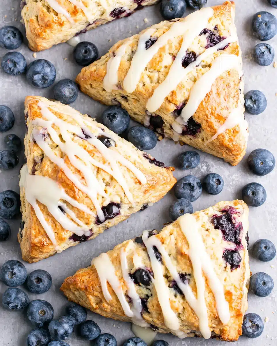 Vegan blueberry scones with white glaze and fresh blueberries on a baking sheet