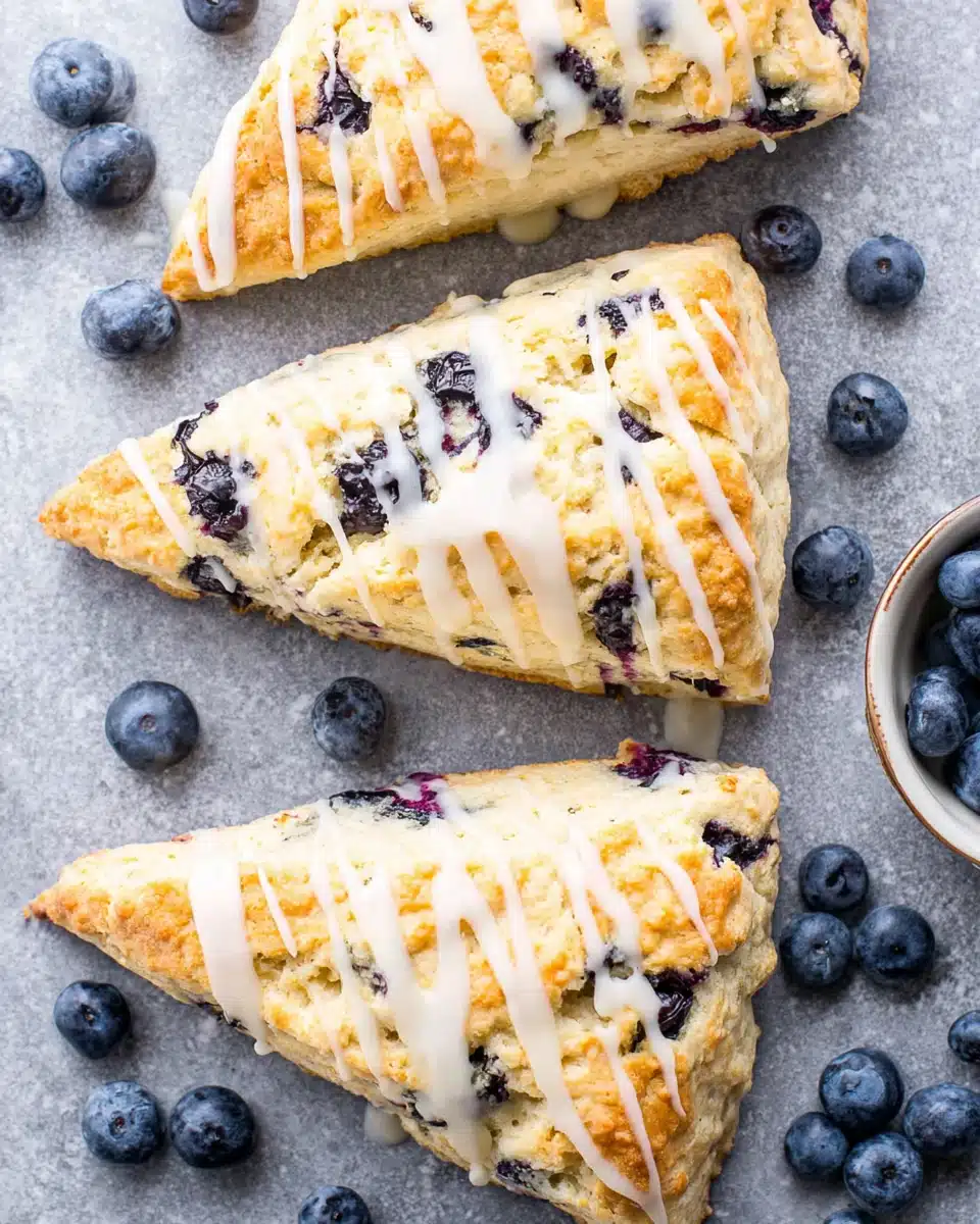 Vegan blueberry scones with white glaze and fresh blueberries on a gray surface